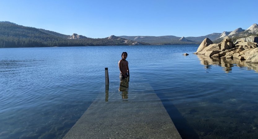 a person stands in waist deep blue water on a backpacking trip for bipoc 